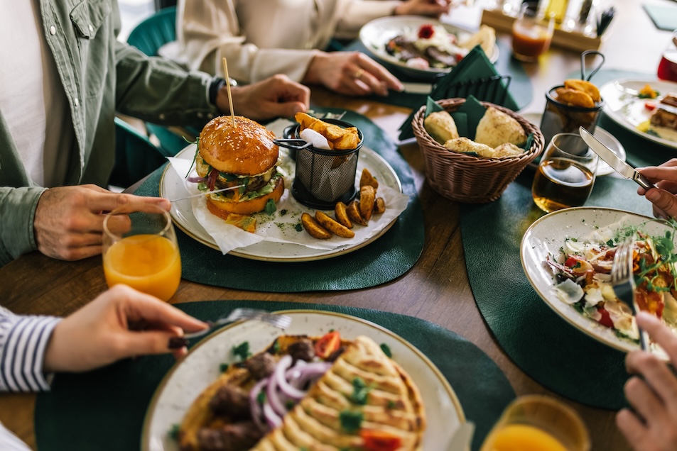 Group of happy friends eating lunch together in a restaurant.