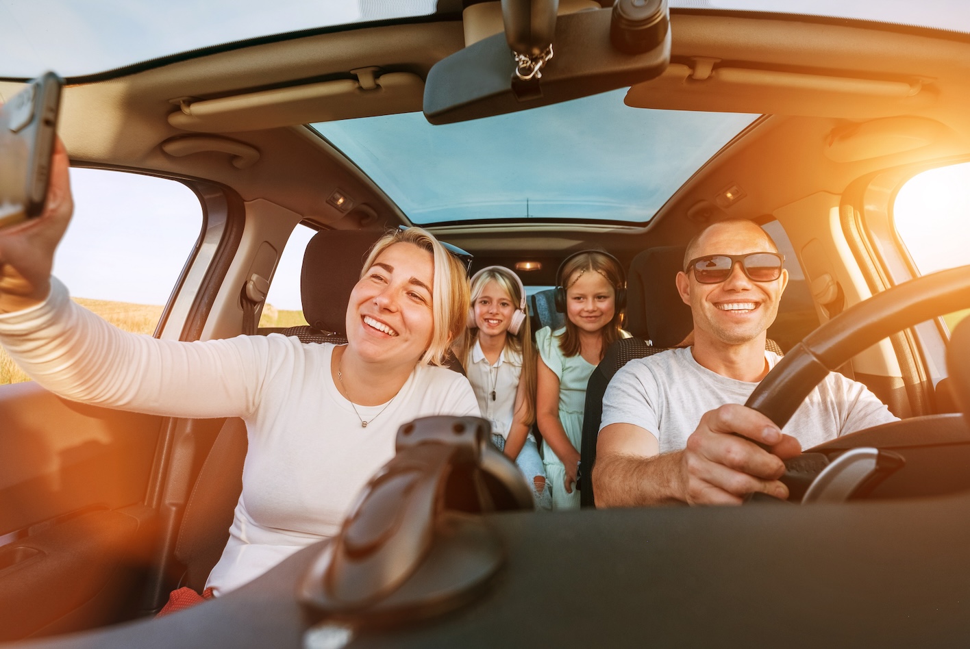 Happy family inside a car, smiling and enjoying a road trip.